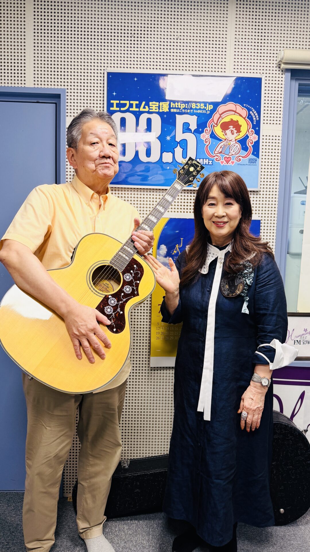 FM宝塚の看板の前でギターを持つ共演者と貴志まさみ